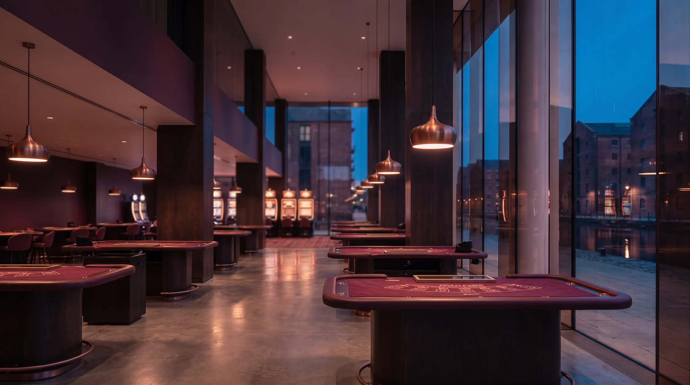 Oxblood-felt tables under copper pendants on The Basin Floor, the canal and brick warehouses beyond the glass