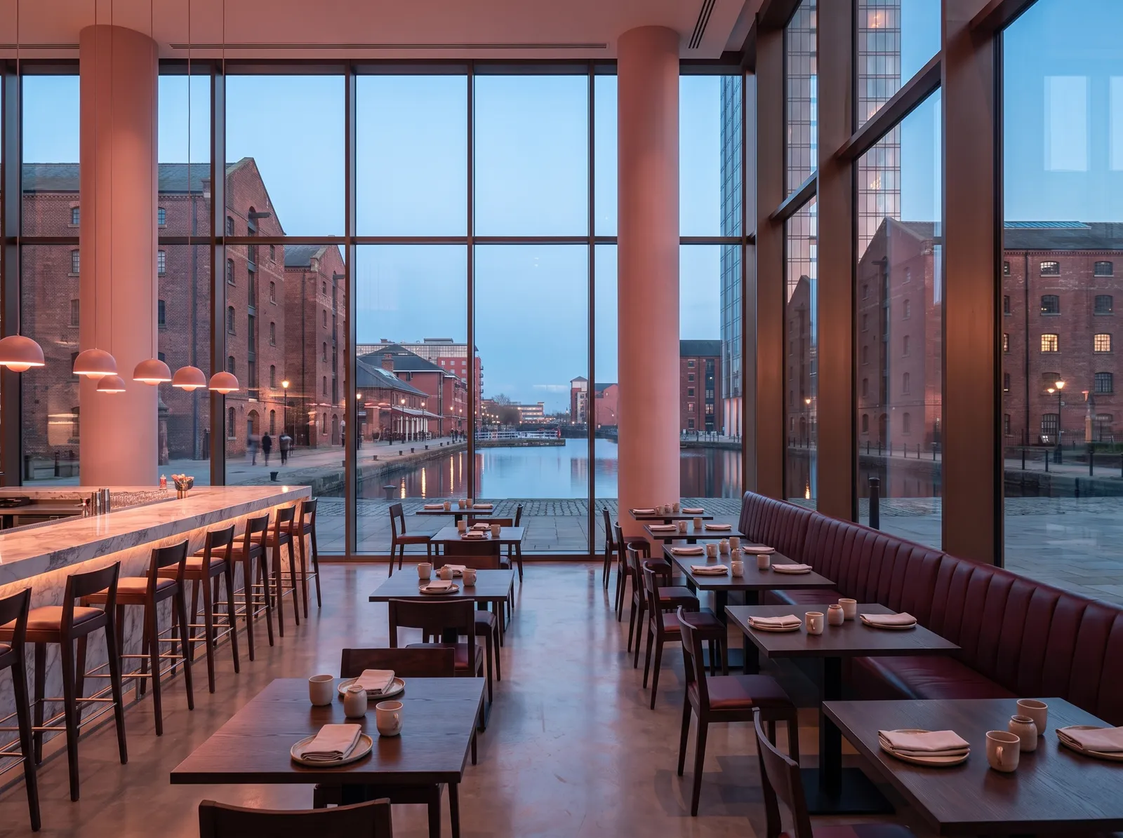 Basin Kitchen: a marble counter and smoked oak tables before tall windows onto the quay